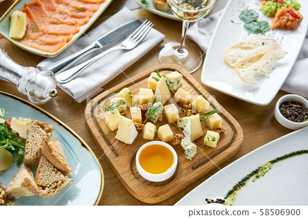 Cheese plate. Focus on delicious cheese mix with walnuts, honey on wooden table. Various snacks and 58506900