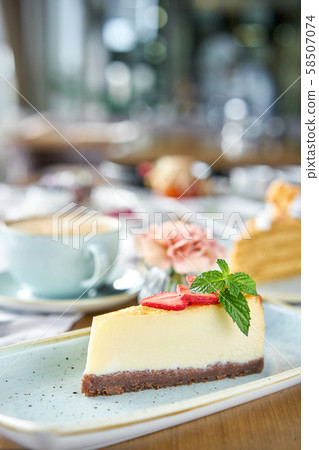Piece of delicious cheesecake with strawberry and mint leaves on white plate. Breakfast in the cafe Piece of delicious cheesecake with strawberry and mint leaves on white plate. Breakfast in the cafe 58507074