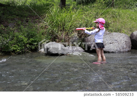 Infant (4 years old) playing in the river with water gun 58509233