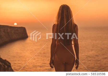 Young woman staying on mountain on shore in body Young woman staying on mountain on shore in body 58510596
