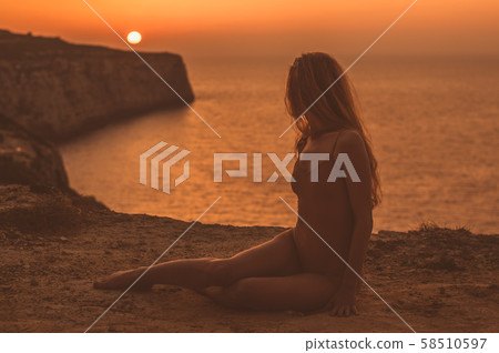 Young woman sitting on mountain on shore in body Young woman sitting on mountain on shore in body 58510597