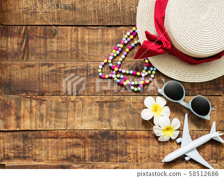 flat lay of hat , necklace , sun glass , flower and red heart shape as traveler's accessories items for summer vacation and plane model on wooden background with copy space. love travel and vacation 58512686