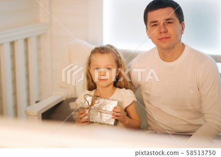 Father with daughter in Christmas time. Dad give a present for his little cure daughter Father with daughter in Christmas time. Dad give a present for his little cure daughter 58513750