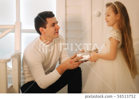 Father with daughter in Christmas time. Dad give a present for his little cure daughter 58513752