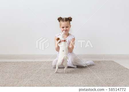 Dogs, children and pets concept - little child girl sitting on the floor with cute puppy 58514772