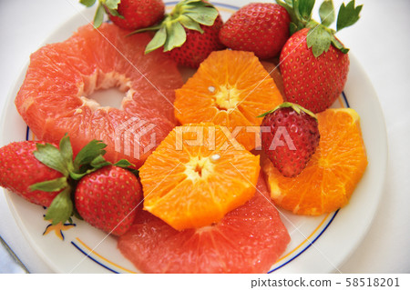 Strawberries and slices of orange and grapefruit on a plate 58518201