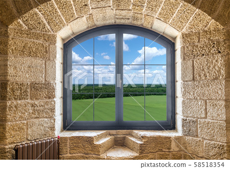 Fragment of a stone wall with a window. Summer landscape outside the window Fragment of a stone wall with a window. Summer landscape outside the window 58518354
