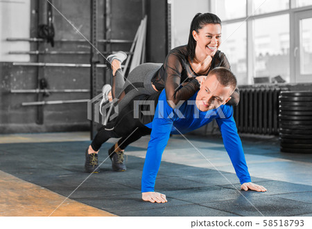 Push-ups with woman on back. Healthy couple in gym, workout with own body weight. Push-ups with woman on back. Healthy couple in gym, workout with own body weight. 58518793