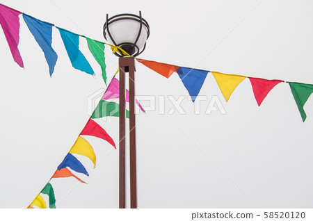 Colorful triangular cloth flags hanging on ropes tied to a lamppost, decoration for festival 58520120