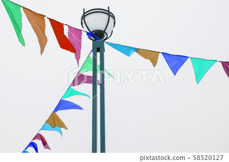 Colorful triangular cloth flags hanging on ropes tied to a lamppost, decoration for festival 58520127