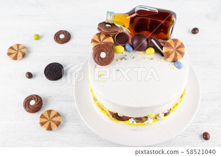 funny cake with a bottle of alcohol, candy and cookies on wooden table 58521040