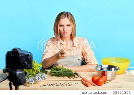 Annoyed female chef points with knife at camera, has angry face expression 58521895