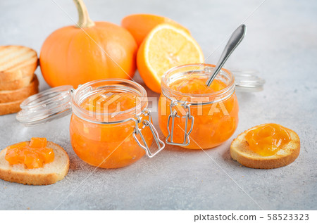 Homemade pumpkin and orange confiture in a jars on a gray concrete background. 58523323