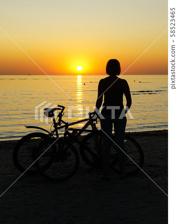 woman silhouette with bicycle at sunset at the sea 58523465