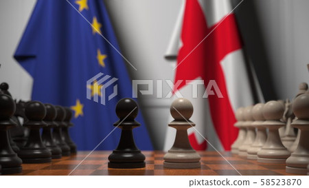 Flags of EU and Georgia behind pawns on the chessboard. Chess game or political rivalry related 3D 58523870