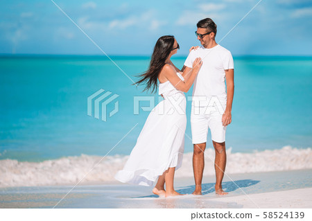 Young couple walking on tropical beach with white sand and turquoise ocean water at Antigua island Young couple walking on tropical beach with white sand and turquoise ocean water at Antigua island 58524139