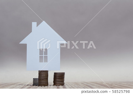 The concept of home from paper on a stack of coins. Horizontal composition. 58525798