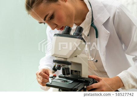 Doctor using microscope in hospital laboratory. Doctor using microscope in hospital laboratory. 58527742