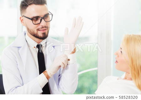 Young dentist talks with patient in dental clinic. Young dentist talks with patient in dental clinic. 58528320