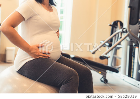 Active pregnant woman exercise in fitness center. Active pregnant woman exercise in fitness center. 58529319