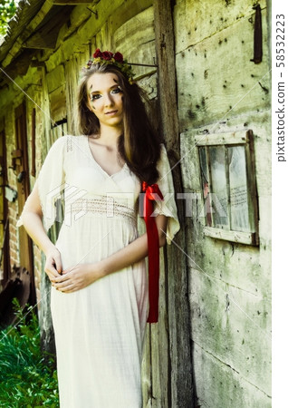 beautiful young woman wearing national ukrainian clothes sitting in wooden hut 58532223