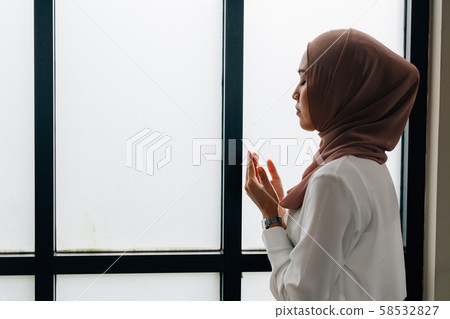 Islamic woman praying near window Islamic woman praying near window 58532827