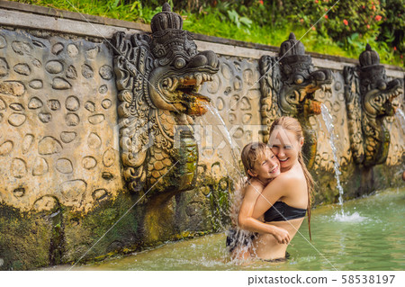 Mom and son travelers in hot springs banjar. Thermal water is released from the mouth of statues at Mom and son travelers in hot springs banjar. Thermal water is released from the mouth of statues at 58538197
