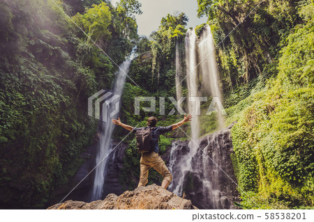 Man in turquoise dress at the Sekumpul waterfalls in jungles on Bali island, Indonesia. Bali Travel 58538201