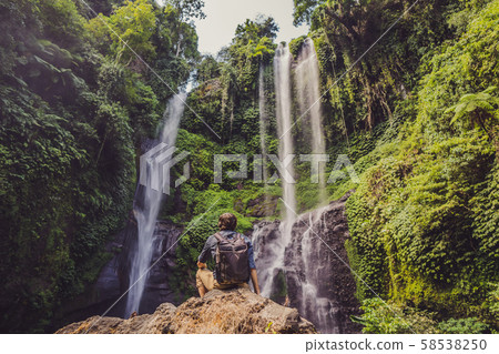 Man in turquoise dress at the Sekumpul waterfalls in jungles on Bali island, Indonesia. Bali Travel 58538250