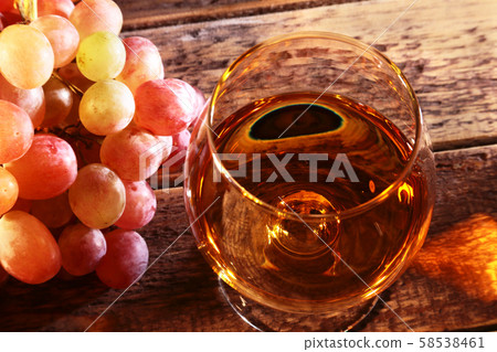Cognac or Brandy in a glass and fresh grapes, still life in rustic style, vintage wooden background Cognac or Brandy in a glass and fresh grapes, still life in rustic style, vintage wooden background 58538461