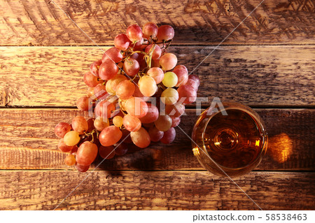 Cognac or Brandy in a glass and fresh grapes, still life in rustic style, vintage wooden background Cognac or Brandy in a glass and fresh grapes, still life in rustic style, vintage wooden background 58538463