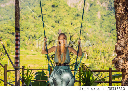 Young woman swinging in the jungle rainforest of Bali island, Indonesia. Swing in the tropics Young woman swinging in the jungle rainforest of Bali island, Indonesia. Swing in the tropics 58538810