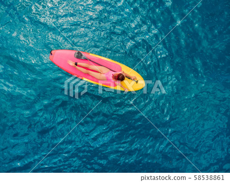 Attractive woman on stand up paddle board on a quiet blue ocean. Sup surfing in tropical sea Attractive woman on stand up paddle board on a quiet blue ocean. Sup surfing in tropical sea 58538861