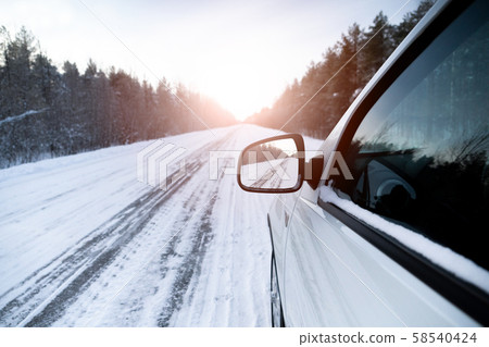 The winter road is reflected in the car's rear-view mirror The winter road is reflected in the car's rear-view mirror 58540424