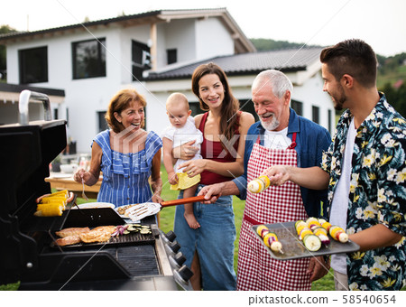 Portrait of multigeneration family outdoors on garden barbecue, grilling. 58540654