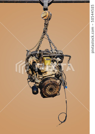 The old engine of the car hung on the hoist. The old engine of the car hung on the hoist. 58544585