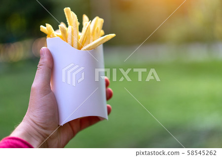 Tasty juicy french fries in white paper box in man 58545262