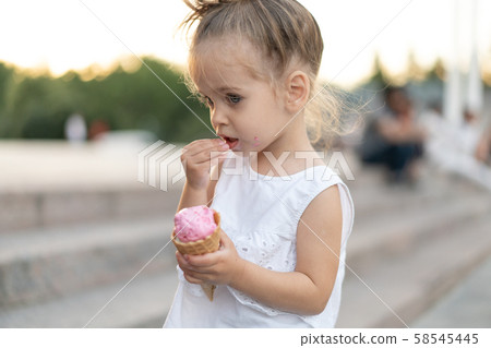 Little caucasian girl 3 years old eats ice cream Little caucasian girl 3 years old eats ice cream 58545445