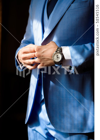 Male businessman dresses and adjusts his watch, preparing for a meeting. Clock 58545516