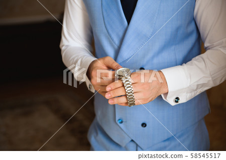 Male businessman dresses and adjusts his watch, preparing for a meeting. Clock 58545517