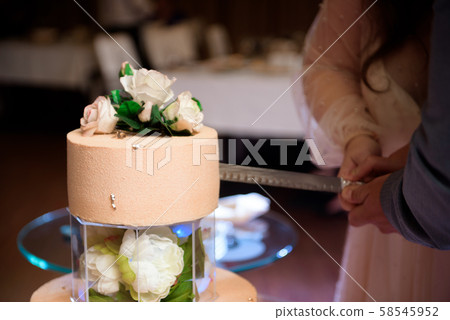 Wedding cake. A bride and a groom is cutting their wedding cake. Wedding cake. A bride and a groom is cutting their wedding cake. 58545952