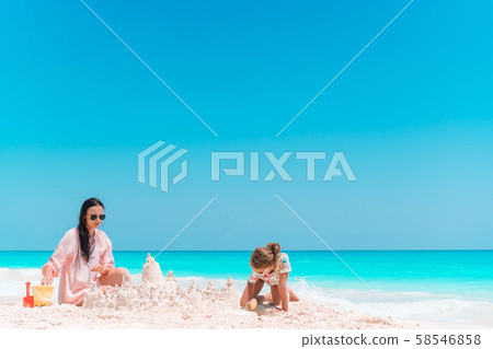 Family making sand castle at tropical white beach. Mother and two girls playing with sand on Family making sand castle at tropical white beach. Mother and two girls playing with sand on 58546858
