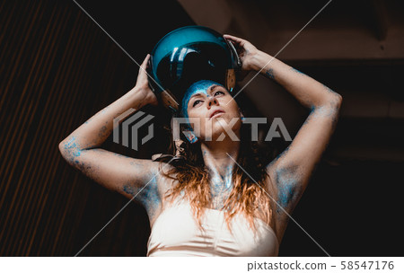 Woman motorcyclist put on crash helmet. Woman with blue sparkles on her face. Woman motorcyclist put on crash helmet. Woman with blue sparkles on her face. 58547176
