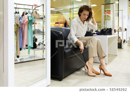 Young woman trying on heels in shop Young woman trying on heels in shop 58549262