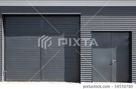 Big and small grey back doors in corrugated metal wall 58550780