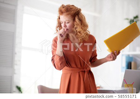Red-haired woman having strong cough at work 58555171