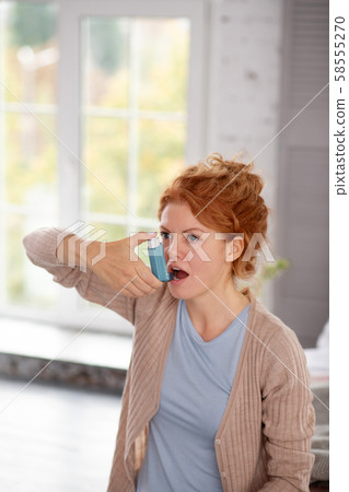 Woman having asthma using inhalator while feeling bad Woman having asthma using inhalator while feeling bad 58555270