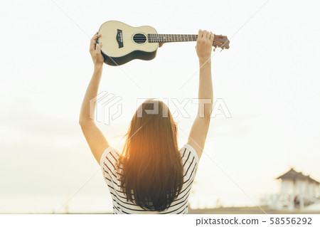 young woman with ukulele view from the back young woman with ukulele view from the back 58556292