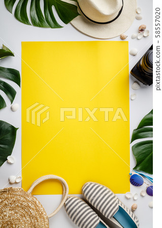 Straw hat, camera, bag, summer shoes, sunglasses, shells and tropical leaves over white and yellow 58557020