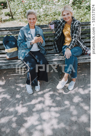 Two smiling friends sitting in a park 58557874